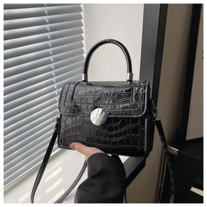 Detail of black crocodile texture bag with round metal rotating buckle and handle