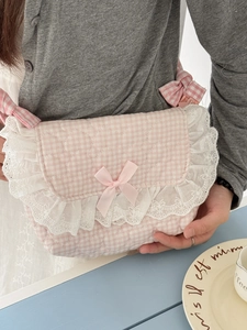 Pink gingham quilted shoulder bag with white lace trim and ribbons shown in a cafe