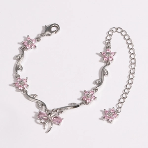 Detail of silver bow bracelet with pink zircon flowers and butterfly charm on white back