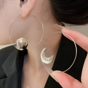 Detail of silver asymmetric earrings with moon and disc pendants in hammered metal