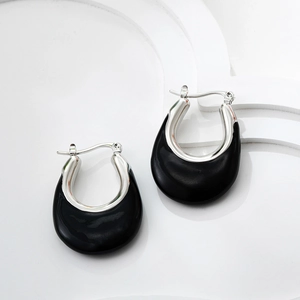 Detailed close-up of U-shaped silver metal earrings with black enamel inlay and glossy finish