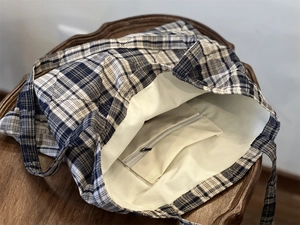 Close-up of quilted plaid tote bag showing inner pocket and zipper on cream lining
