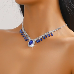 Macro detail of silver necklace featuring blue square gemstone and crystal pendants