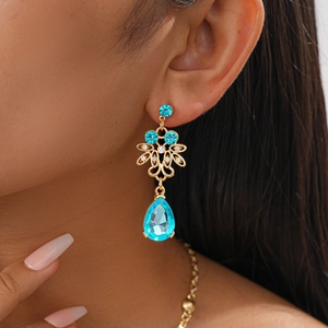 Detailed close-up of a vintage golden earring with blue water-drop crystals on a model