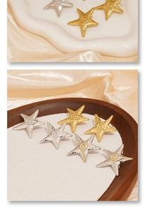 Detailed close-up of starfish-shaped earrings in gold and silver on a decorative tray