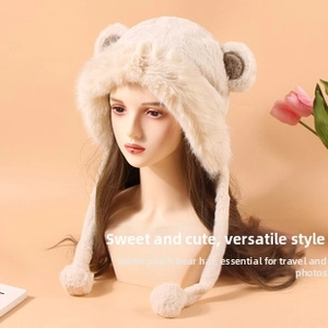 Détail du bonnet en peluche beige avec oreilles d'ours et liens à pompons décoratifs