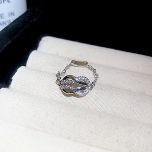 Macro shot of silver infinity knot chain ring with micro-set crystals on a jewelry tray