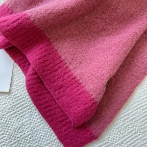 Close-up of the soft cashmere-like knit fabric with pink color-block and ribbed edge