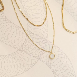 Detail of double-layer gold necklace with round white mother-of-pearl pendant