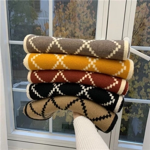 Close-up of stacked knit scarves showing various geometric diamond patterns and colors