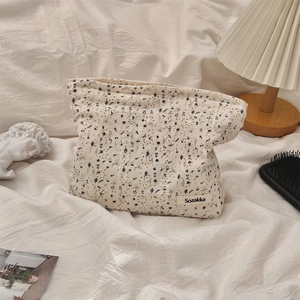 Detailed shot of floral canvas makeup bag on a soft fabric background with lifestyle props