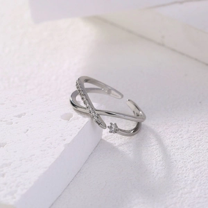 Elegant silver criss-cross adjustable ring with pavé zircons on white stone texture