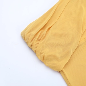 Detailed macro shot of yellow mesh fabric texture and pleated craftsmanship on the dress
