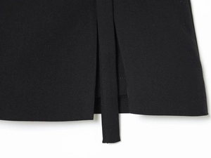 Close-up of black woven fabric featuring detailed slit design and decorative ribbon tie