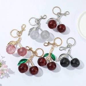 Detailed flat lay of cherry keychains in red, pink and black with glitter resin finish
