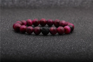 Detail of rose red tiger eye beads and black lava stone on an elastic bracelet