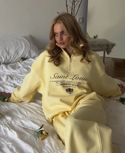 Close-up of pale yellow half-zip sweatshirt with Saint Louis embroidery and soft cotton texture