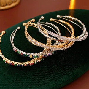 Close-up of luxury crossed zircon bracelets with colorful stones on green velvet