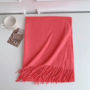 Detail of coral cashmere-feel scarf with elegant fringes and soft fabric texture