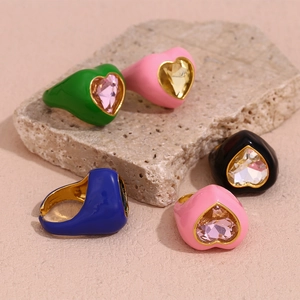Detailed view of 18K gold plated heart rings with colorful enamel on a natural stone
