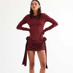 Détail de la fleur 3D et des rubans élégants sur la robe moulante de couleur bordeaux