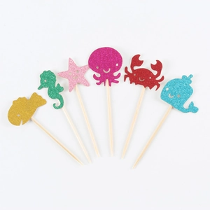 Close-up of glitter mermaid party cake toppers featuring sea animals on white background