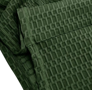 Macro de leggings de sport vert foncé montrant la texture alvéolée et les coutures doubles