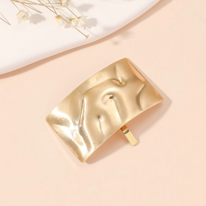 Detailed macro view of a gold metallic ponytail clip with an irregular hammered texture