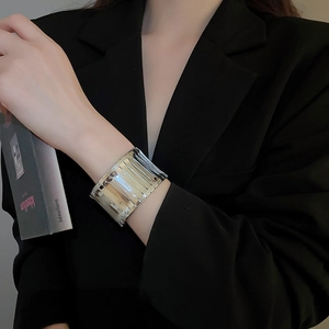 Detail showing irregular wide silver cuff bracelet with vertical striped texture and high shine