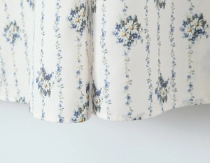 Close-up of white summer dress hem featuring blue floral and vine print patterns