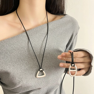 Detail of silver geometric flower pendants on black leather cords worn by a model