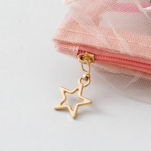 Close-up of golden star zipper on pink mesh cosmetic bag showing detailed craftsmanship