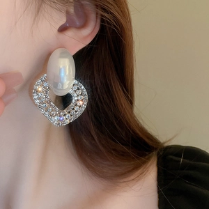Close-up of heart-shaped drop earrings with faux pearls and rhinestones on model