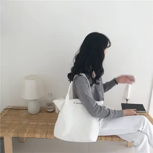 Detalle de bolso tote de lona blanca con letras mercipa en un ambiente de estilo de vida