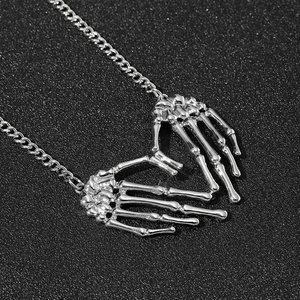 Gothic punk skeleton hand heart pendant necklace in silver finish on black background