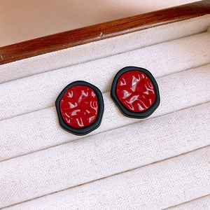 Macro view of vintage irregular round red textured earrings with black matte borders
