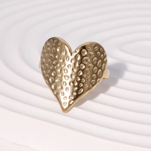 Polished gold hammered heart ring in stainless steel displayed on a white textured tray