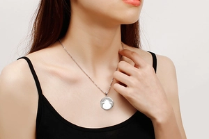 Macro detail of a silver necklace featuring a hollow pineapple pendant on a model