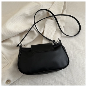 Detail view of black faux leather handbag with silver hardware on white corduroy fabric