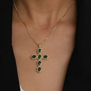 Cross necklace with green zircons and gold plating on model with black suit