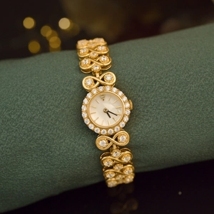 Detailed view of luxury gold vintage watch with diamond bezel on green fabric roll