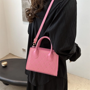 Pink quilted crossbody bag with metal buckle shown on a model in a minimalist setting
