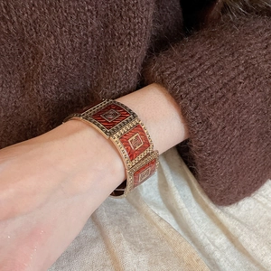Detail of vintage gold bracelet with red enamel squares and spiral engraved patterns