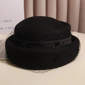 Detail of elegant black wool beret with delicate mesh veil and satin ribbon trim