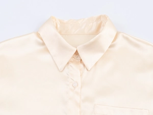 Detaillierte Makroansicht von klassischem Kragen und Satin-Textur an der beige Bluse