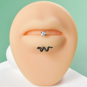 Macro shot of silver zircon labret and black snake stud on a silicone lip model