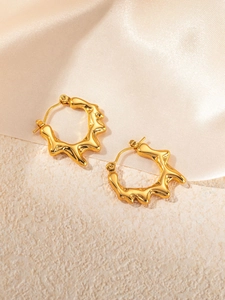 Detailed view of gold stainless steel earrings with irregular water ripple texture on silk