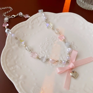 Detail of beaded necklace featuring pink bow star beads and a heart metal pendant