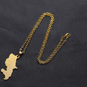 Close-up of gold stainless steel Martinique map pendant on black leather surface