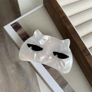 Detail of white acetate cat hair claw clip with pearlescent finish on minimalist book